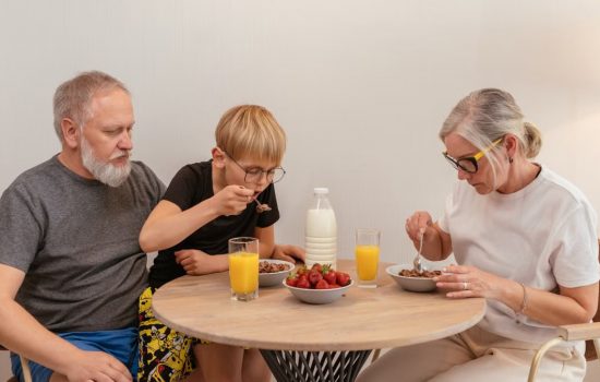 A family of three enjoying breakfast around a wooden table at home.